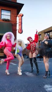 A group of excited drag queens posing on the street in front of the Hood River Hotel